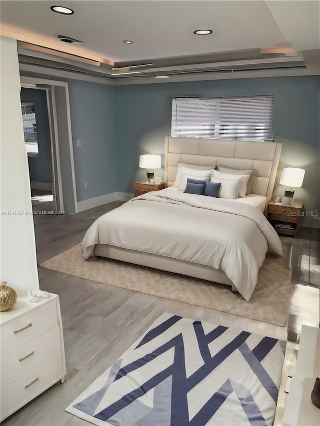 bedroom with a raised ceiling and light hardwood / wood-style flooring