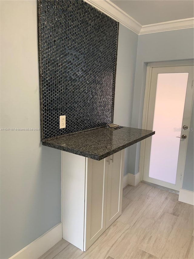 kitchen with decorative backsplash, kitchen peninsula, white cabinetry, and ornamental molding