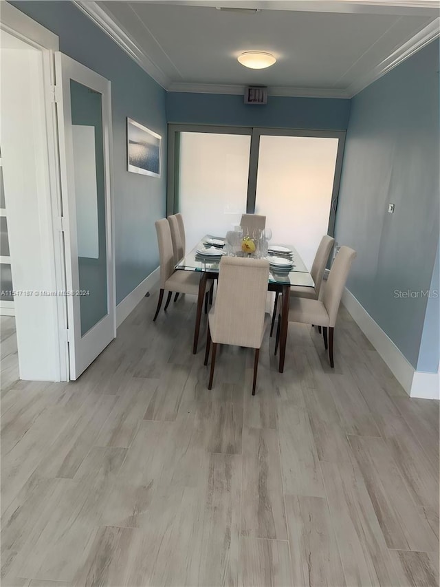 dining room with light hardwood / wood-style flooring and crown molding