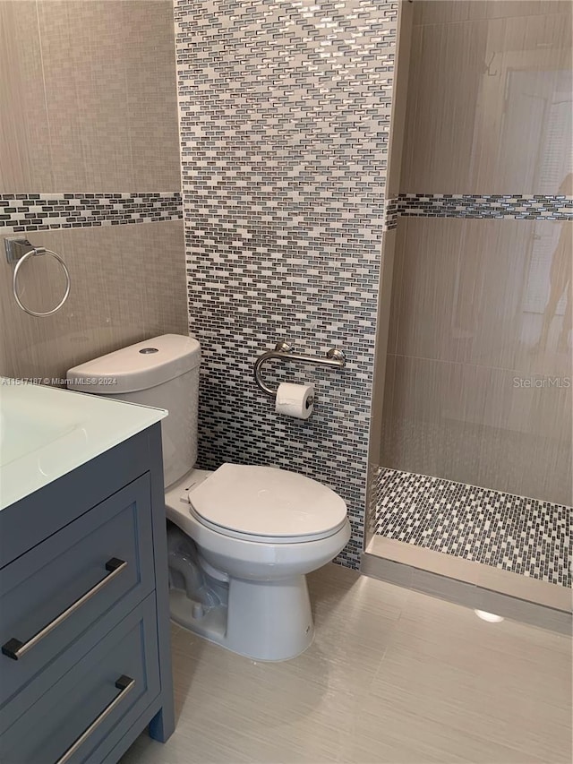 bathroom with tile patterned floors, vanity, toilet, and tile walls