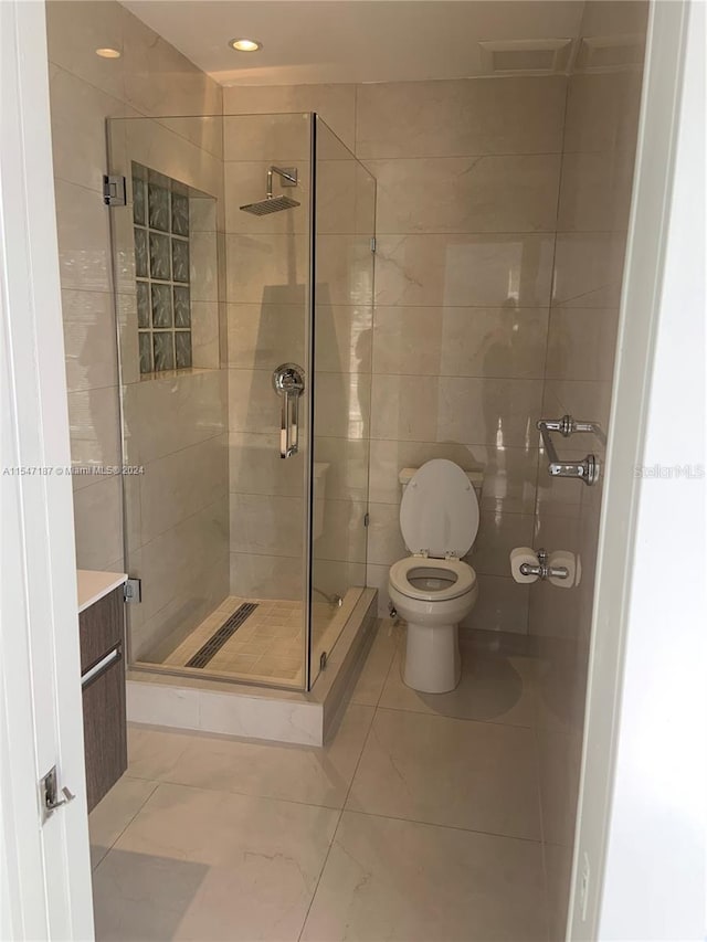 bathroom with vanity, tile patterned floors, toilet, tile walls, and an enclosed shower