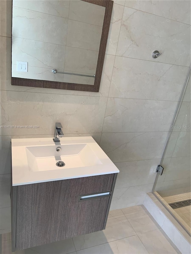 bathroom with vanity, a tile shower, and tile walls