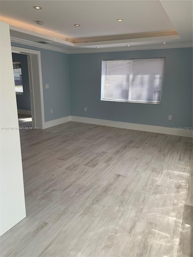 spare room with light hardwood / wood-style flooring and a tray ceiling