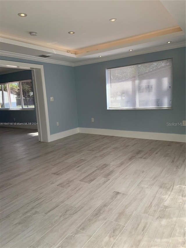 unfurnished room with light hardwood / wood-style flooring and a tray ceiling