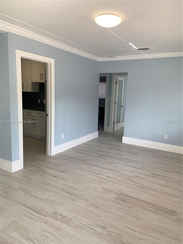 unfurnished room with light hardwood / wood-style floors and crown molding