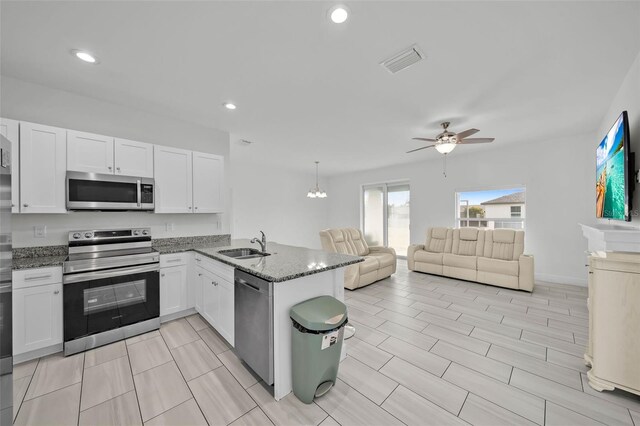 kitchen with kitchen peninsula, appliances with stainless steel finishes, and white cabinets