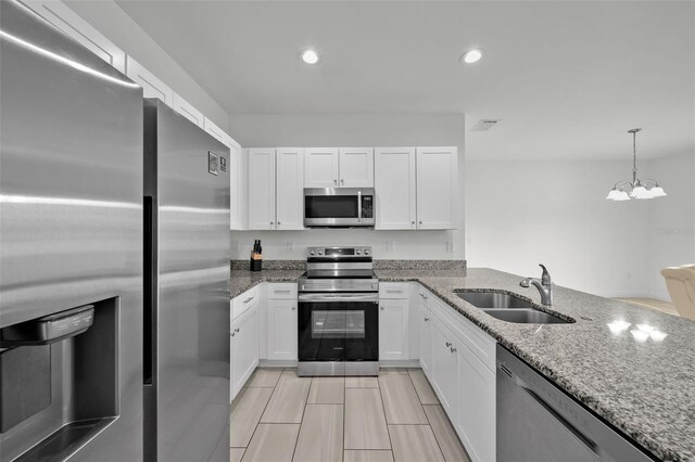 kitchen featuring an inviting chandelier, sink, stone countertops, white cabinetry, and stainless steel appliances