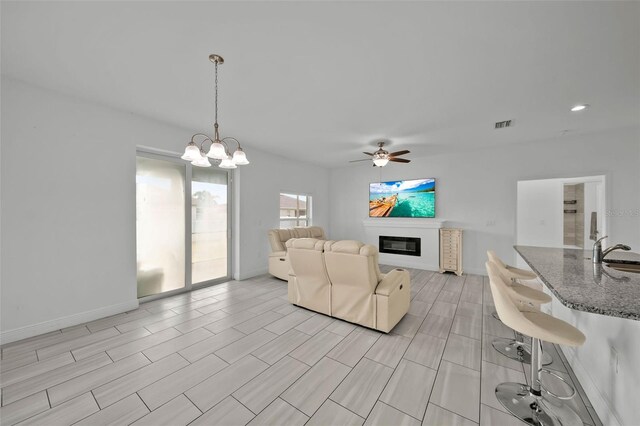 living room featuring ceiling fan with notable chandelier and sink