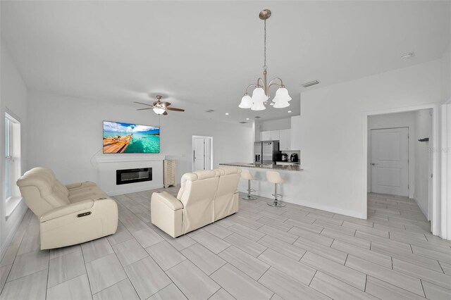 unfurnished living room featuring ceiling fan with notable chandelier