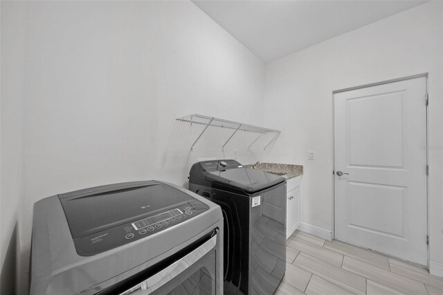 laundry area with cabinets and washing machine and clothes dryer