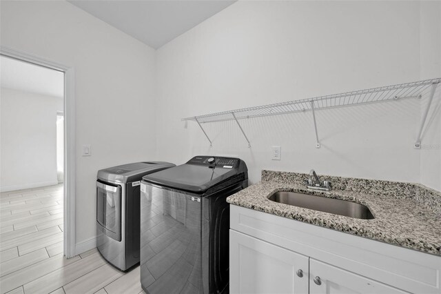 laundry room featuring cabinets, sink, and washing machine and clothes dryer