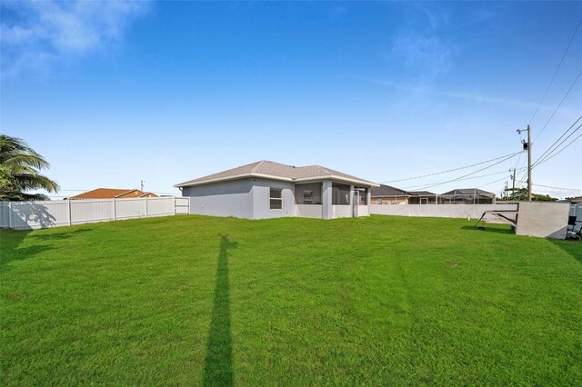 back of house featuring a lawn and a sunroom