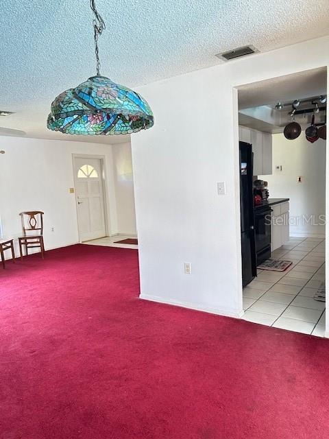 interior space with light carpet, visible vents, and a textured ceiling