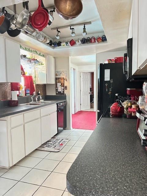 kitchen featuring white cabinets, a sink, black appliances, and dark countertops