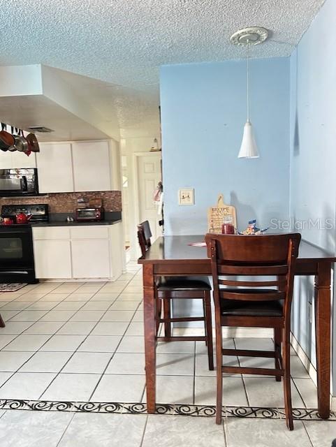 dining area with a textured ceiling and light tile patterned floors