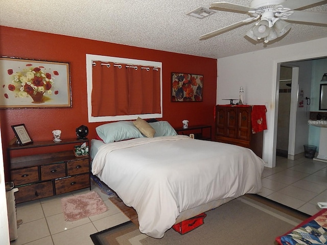 tiled bedroom featuring visible vents, ceiling fan, ensuite bathroom, and a textured ceiling