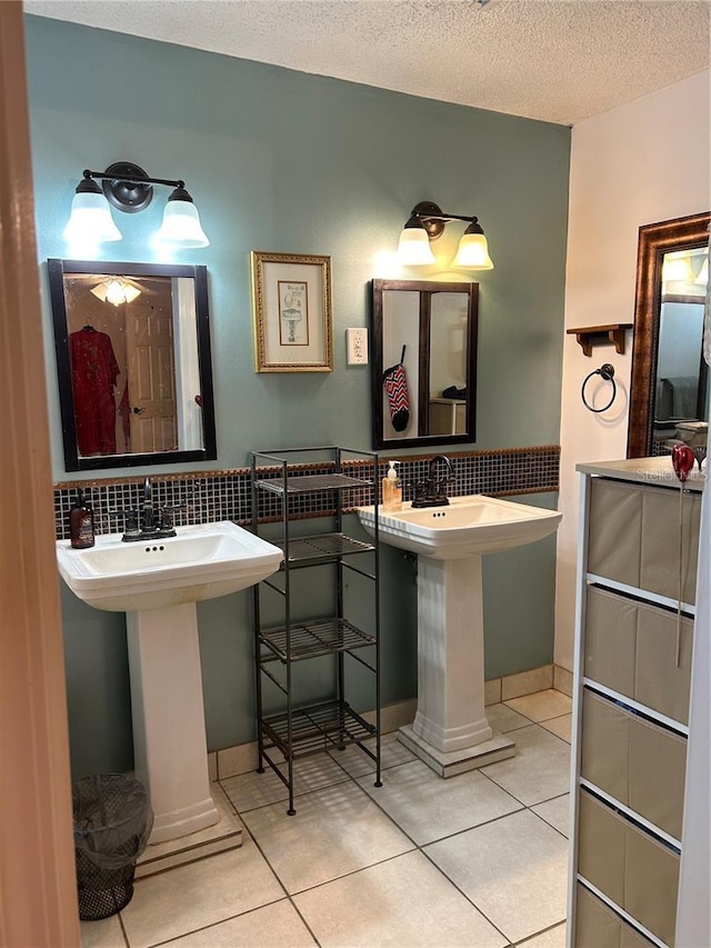 bathroom with tasteful backsplash, tile patterned floors, a sink, and a textured ceiling