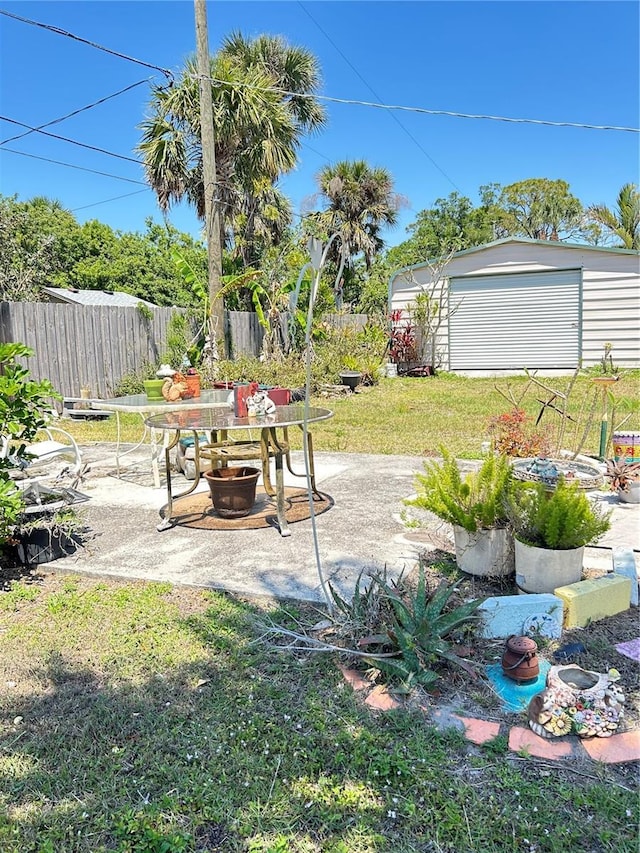 view of yard featuring a patio, fence, and an outbuilding