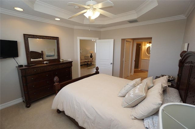 carpeted bedroom with a tray ceiling, connected bathroom, ceiling fan, and ornamental molding