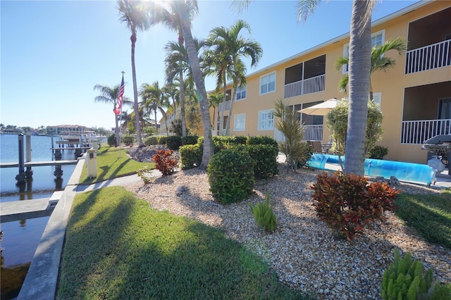 view of property's community with a yard, a water view, and a boat dock