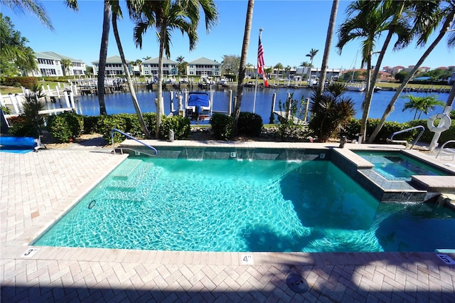 view of swimming pool with pool water feature, a water view, and an in ground hot tub