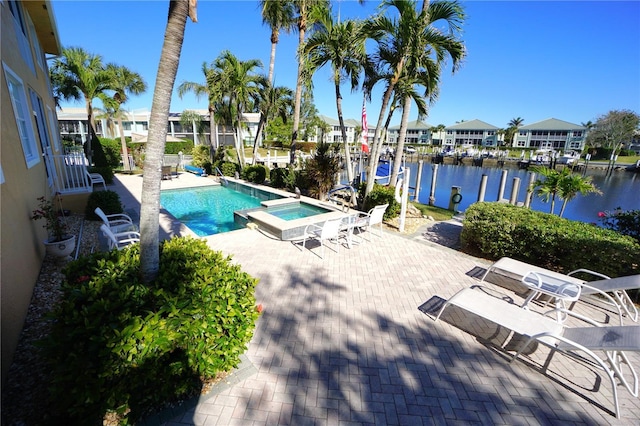 view of pool featuring a water view, an in ground hot tub, and a patio