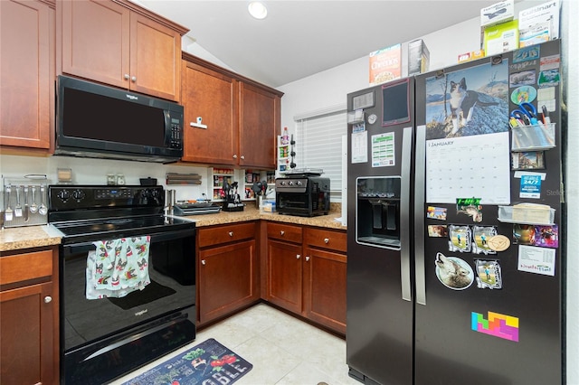 kitchen with light tile patterned floors, light stone counters, black appliances, and lofted ceiling