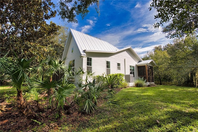 view of property exterior with a sunroom, central AC, and a lawn