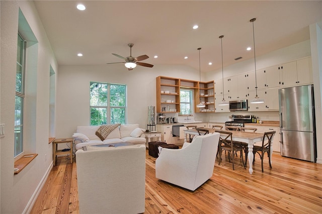 living room with ceiling fan, lofted ceiling, and light hardwood / wood-style flooring