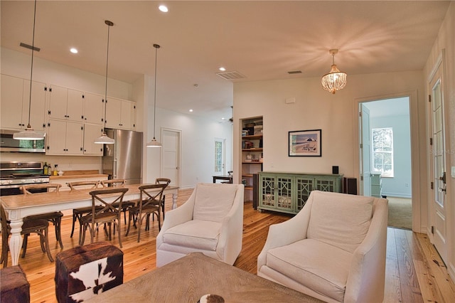 living room featuring light wood-type flooring, an inviting chandelier, and lofted ceiling