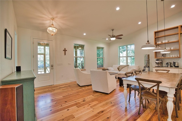 living room with ceiling fan with notable chandelier and light wood-type flooring