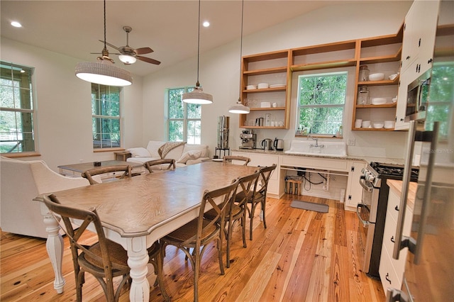 dining room featuring ceiling fan, sink, lofted ceiling, and light wood-type flooring