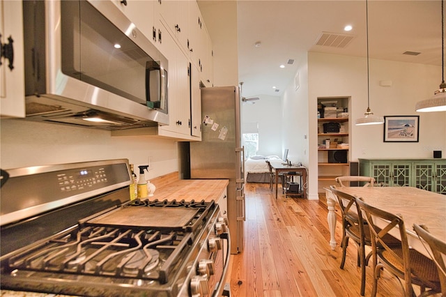 kitchen with white cabinets, stainless steel appliances, light hardwood / wood-style flooring, and hanging light fixtures