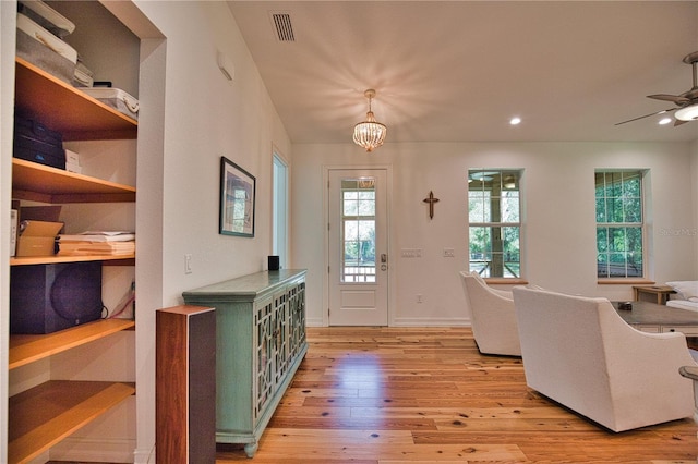 entryway featuring ceiling fan with notable chandelier and light hardwood / wood-style flooring