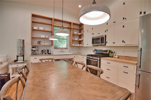 kitchen with sink, stainless steel appliances, hanging light fixtures, and vaulted ceiling