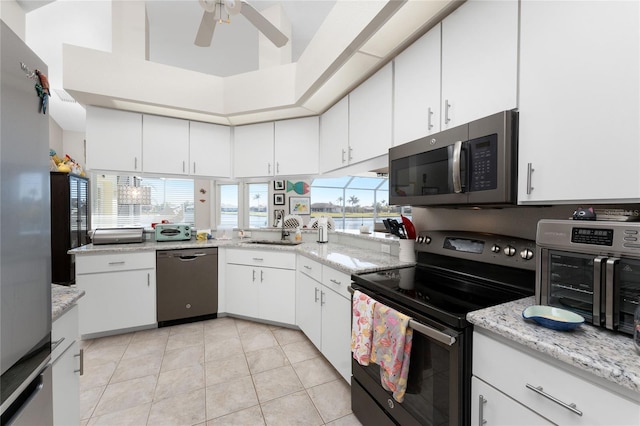 kitchen with light tile patterned floors, a towering ceiling, stainless steel appliances, and white cabinetry