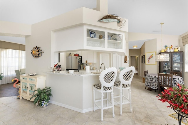 kitchen with pendant lighting, stainless steel fridge, light tile patterned floors, and kitchen peninsula