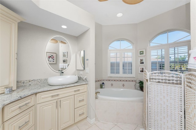 bathroom featuring tile patterned floors, vanity, and a relaxing tiled tub