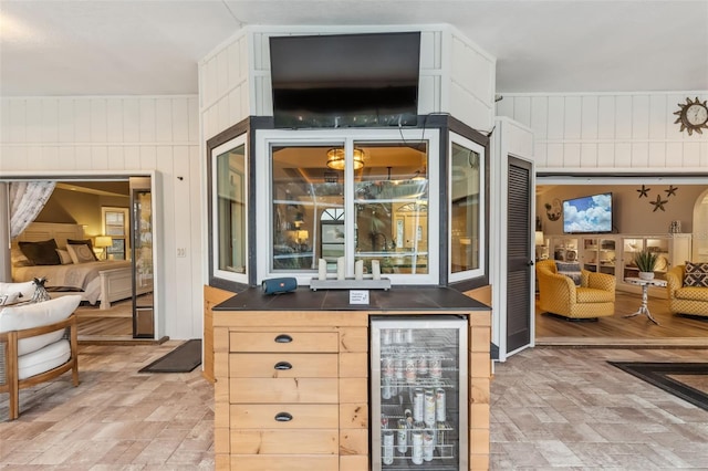 bar featuring wine cooler, wooden walls, and light brown cabinets