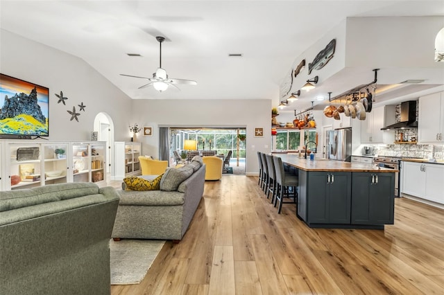 living room featuring vaulted ceiling, sink, ceiling fan, and light hardwood / wood-style flooring