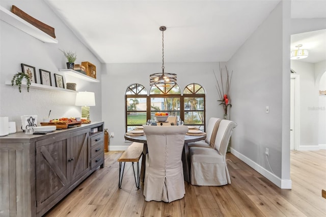 dining room with light hardwood / wood-style flooring and vaulted ceiling