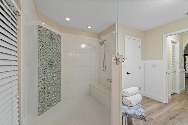 bathroom featuring wood-type flooring, a tile shower, and a textured ceiling