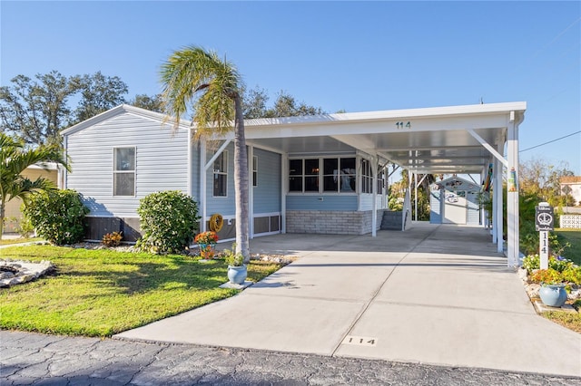 manufactured / mobile home with a carport, a storage unit, and a front lawn