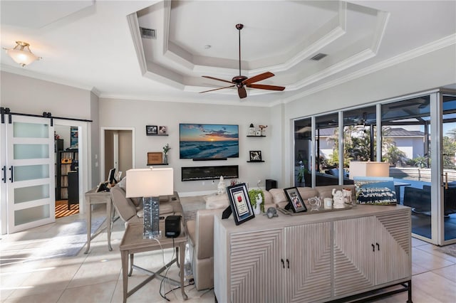 tiled living room featuring a barn door, crown molding, a raised ceiling, and ceiling fan