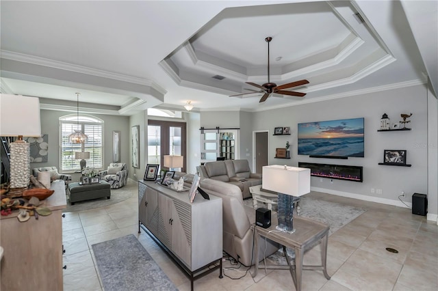 living room with ornamental molding, light tile patterned flooring, ceiling fan with notable chandelier, and a tray ceiling