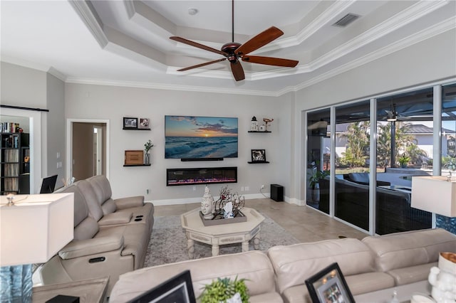 tiled living room featuring ceiling fan, a tray ceiling, and crown molding