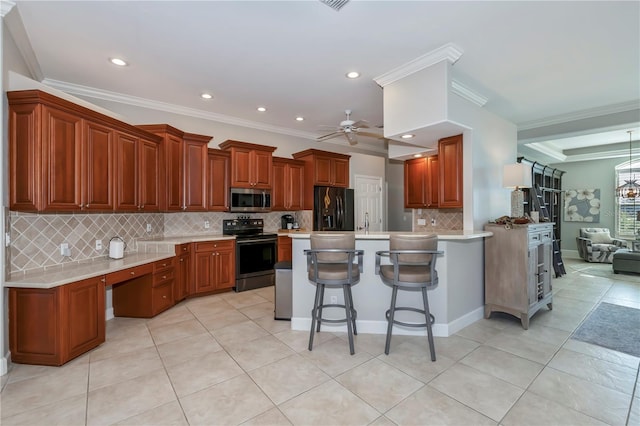 kitchen featuring stainless steel appliances, ornamental molding, ceiling fan, a kitchen bar, and a kitchen island