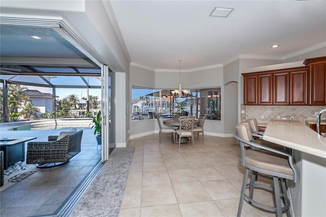 kitchen featuring a chandelier, pendant lighting, light tile patterned floors, decorative backsplash, and crown molding