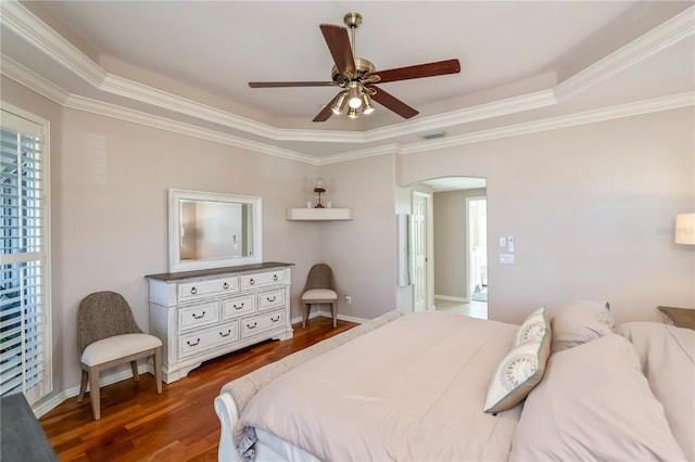 bedroom featuring dark hardwood / wood-style flooring, multiple windows, ceiling fan, and a tray ceiling