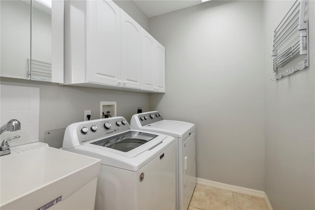 clothes washing area featuring sink, washer and clothes dryer, light tile patterned floors, and cabinets